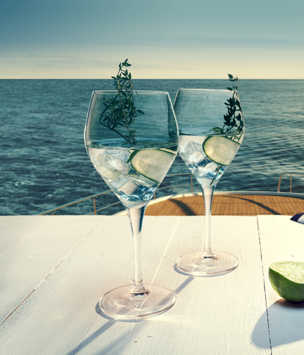 바다 위 크루즈 선상에서 와인잔 두 개가 놓인 테이블과 LUXURY Cruise 골드 배지가 있는 럭셔리한 분위기